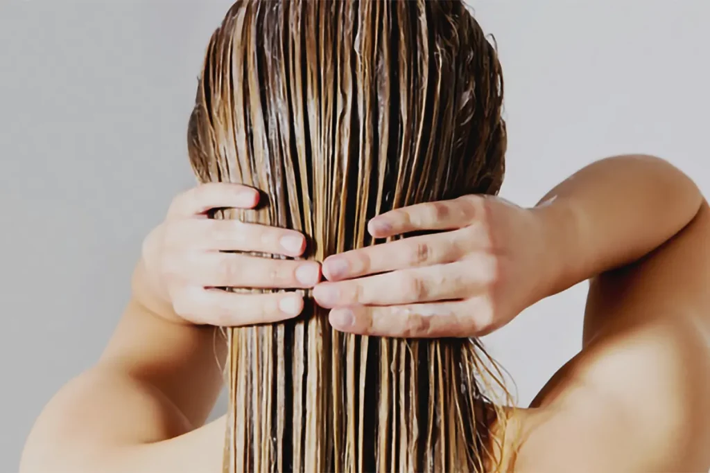 A woman is holding her hair in front of her face.