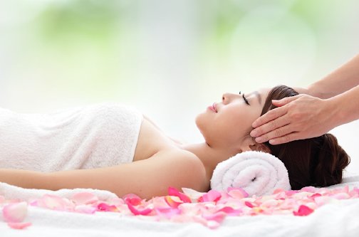Woman receiving relaxing head massage with petals.