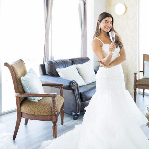 Bride holding champagne glass in elegant room.