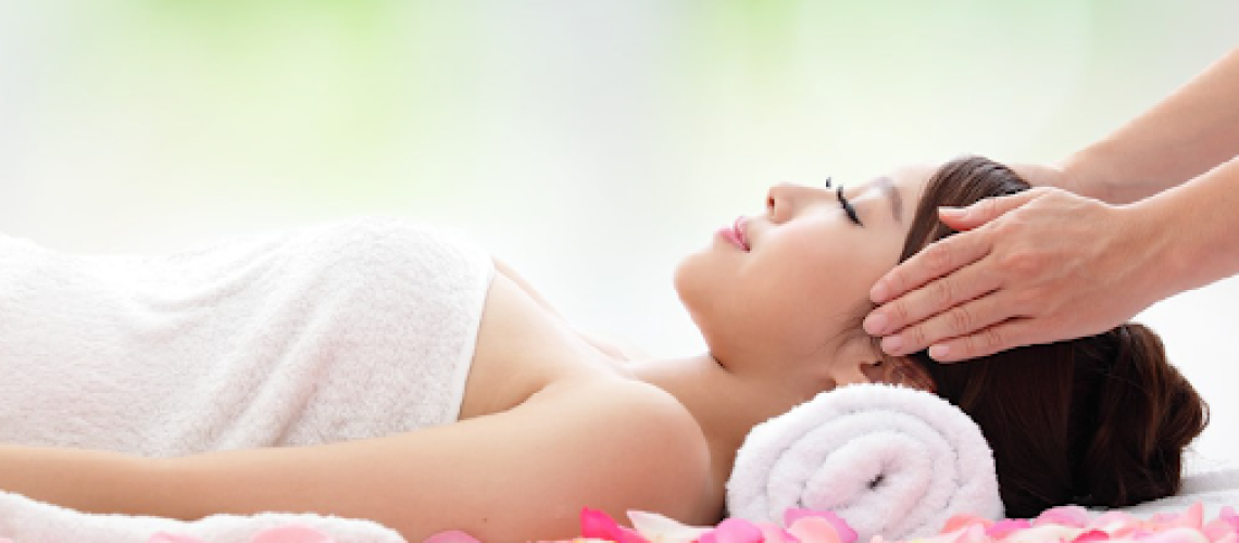 Woman receiving relaxing head massage with petals.